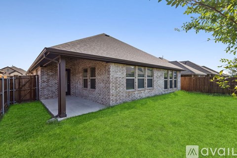 A house with a brown roof and a brick exterior is surrounded by a green lawn.