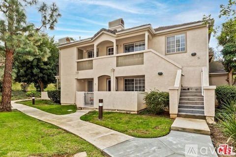 A beige two-story house with a front yard and a driveway.