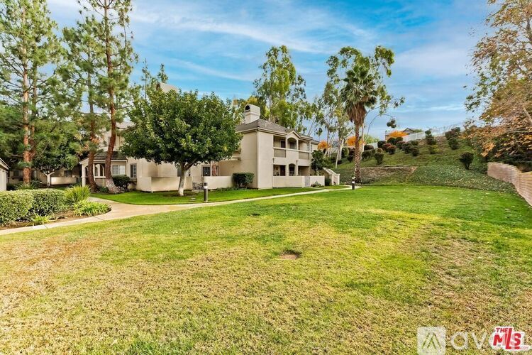 A large, well-maintained house with a spacious lawn and trees in the background.