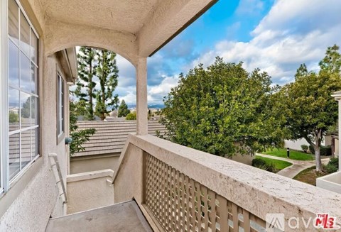 A balcony with a view of a tree-lined street.