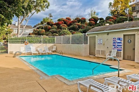 A pool surrounded by a fence and chairs.