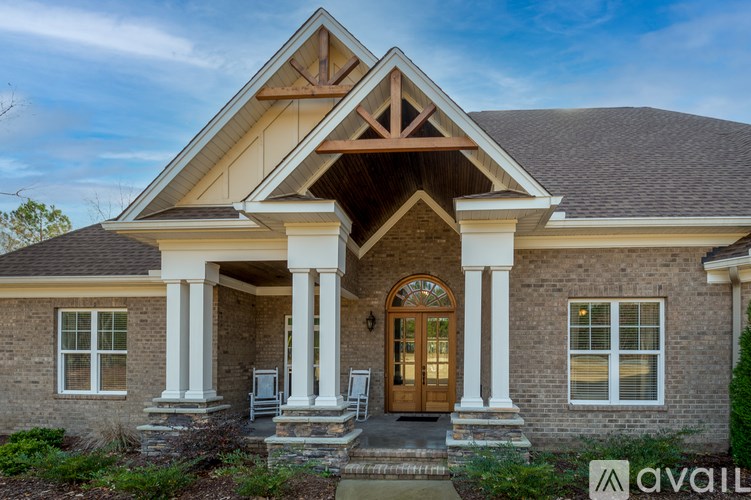A house with a brown door and a porch with four white columns.