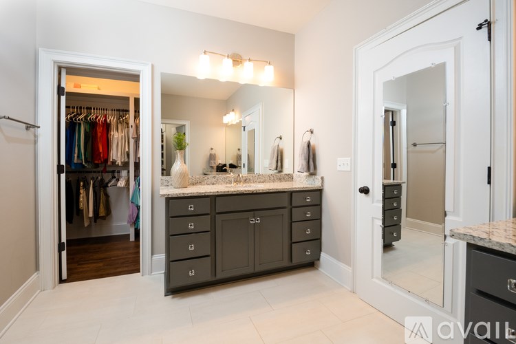 A spacious bathroom with a walk-in closet and a vanity with a mirror above it.