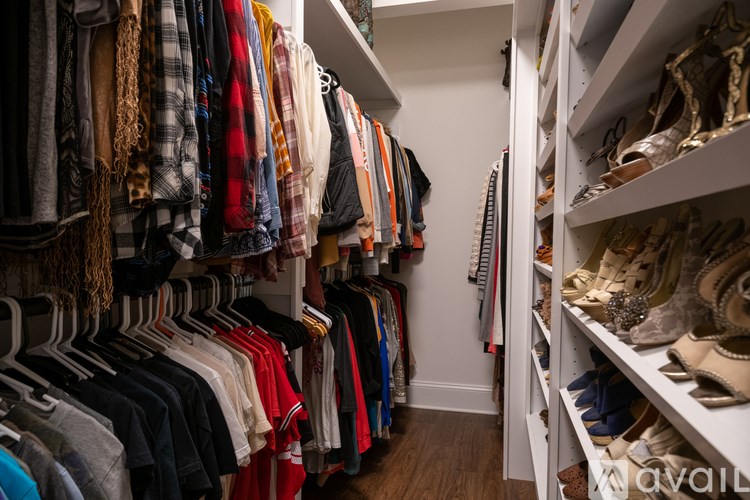 A walk in closet with clothes and shoes.