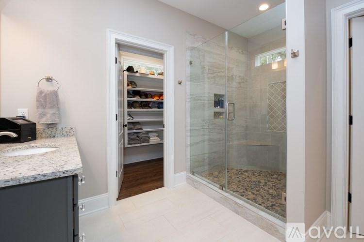 A walk-in closet with a marble countertop and a glass door.