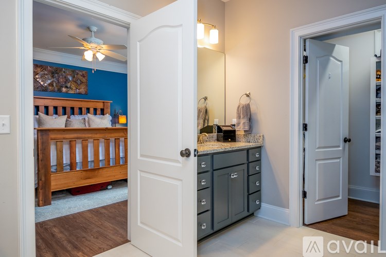 A white door opens to a room with a bed and a vanity.