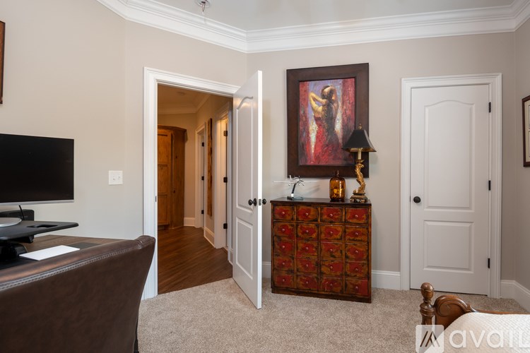 A brown leather couch sits in a living room with a television and a painting on the wall.