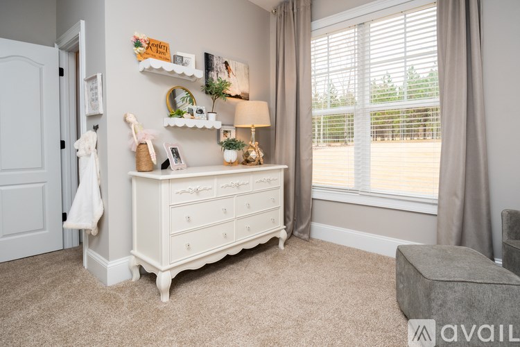 A white dresser with a mirror and a coat hanging on the wall.