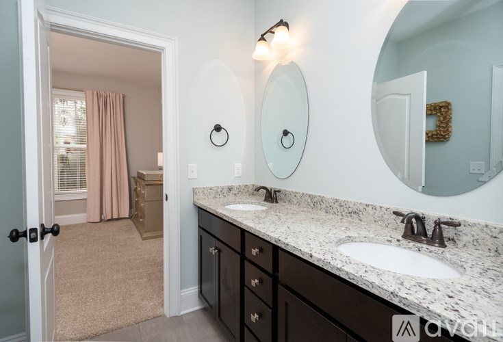 A bathroom with a sink, mirror, and a door leading to a bedroom.