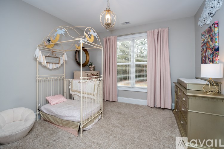 A baby's room with a white canopy bed and a white dresser.