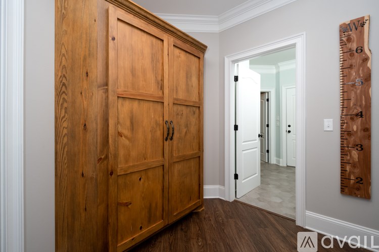 A wooden cabinet with a door and a ruler on the wall.