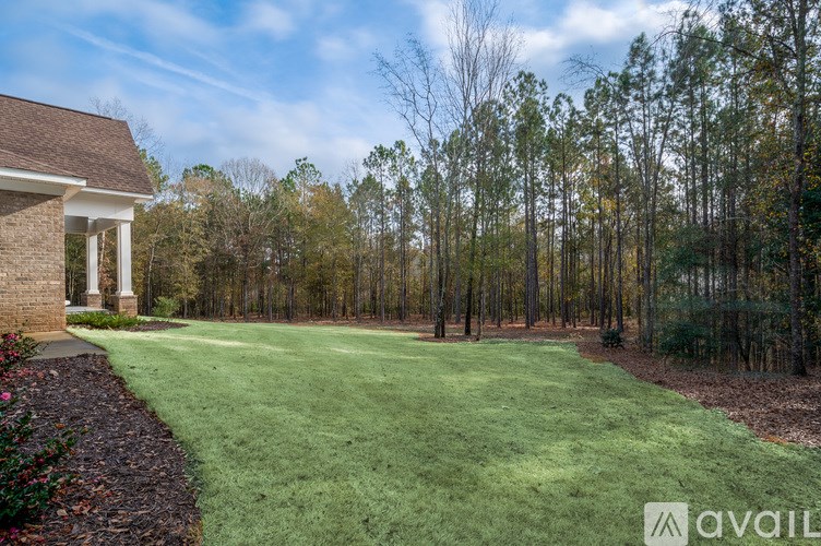 A house with a well-maintained lawn and trees in the background.