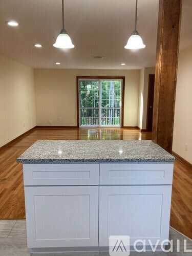 A kitchen with a granite countertop and wooden floors.