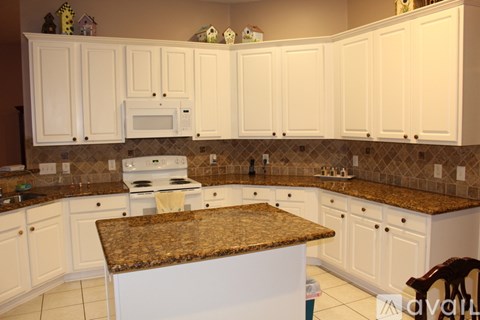 A kitchen with white cabinets and a granite countertop.