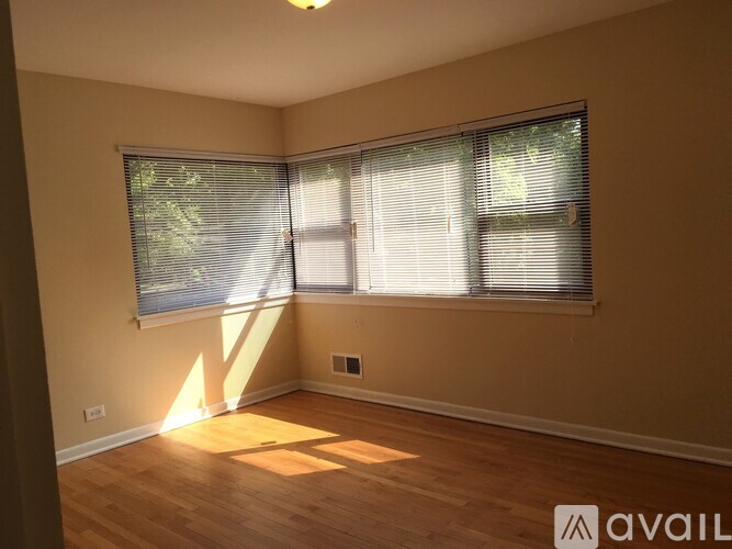 A room with wooden floors and a window with blinds.