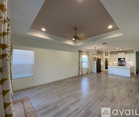 A spacious living room with a ceiling fan and lighting fixtures.