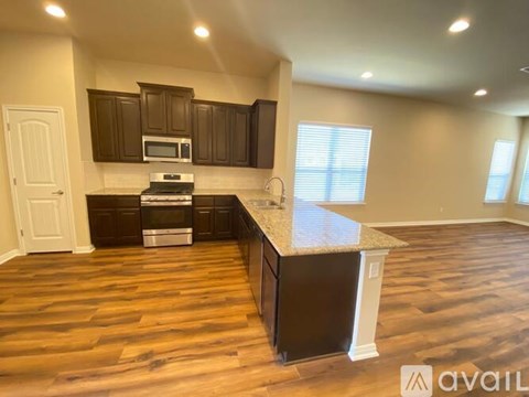 A kitchen with dark wood cabinets and a granite countertop.