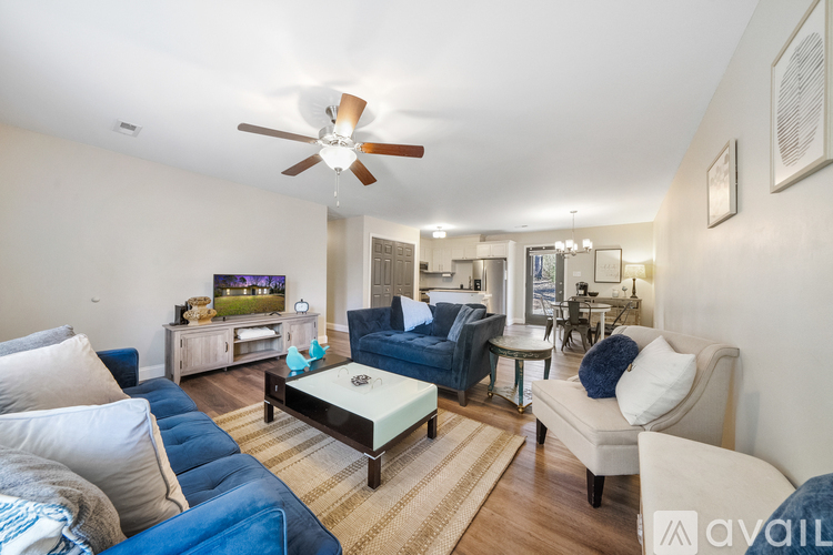 A living room with a white ceiling fan and a television on a wooden cabinet.