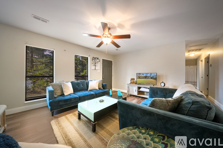 A living room with a blue couch and a ceiling fan.