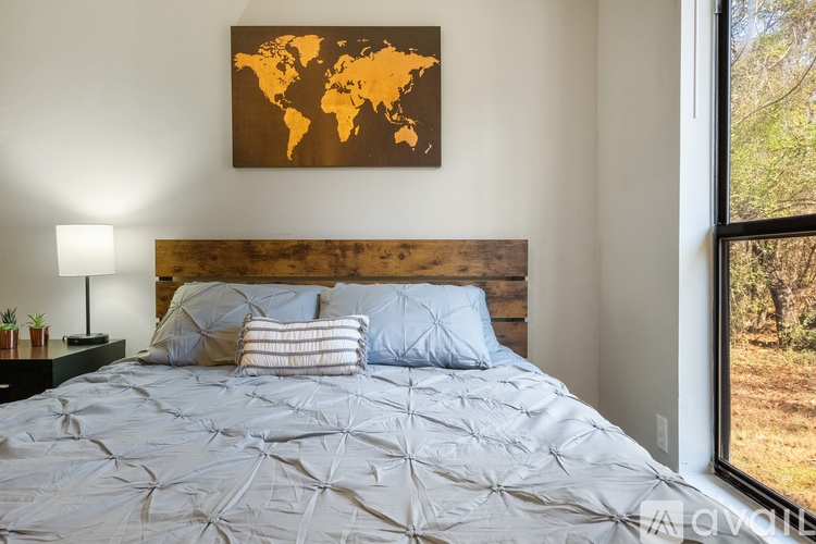 A bedroom with a world map on the wall and a bed with a grey comforter.