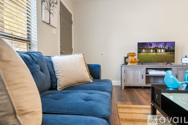 A blue couch with a white pillow is in the foreground of a living room.
