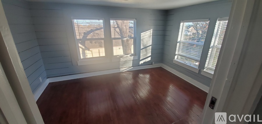 A room with wooden floors and a window with blinds.