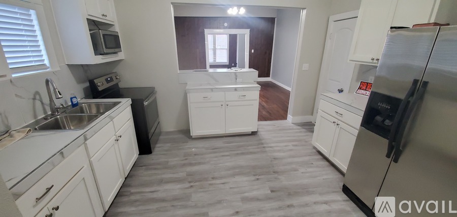 A kitchen with white cabinets and a black counter top.