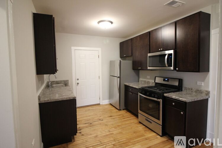 A kitchen with black cabinets and a stainless steel oven.