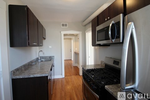 A kitchen with black cabinets and a stainless steel oven.