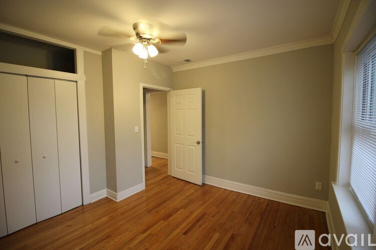 A room with wooden floors and a window with blinds.