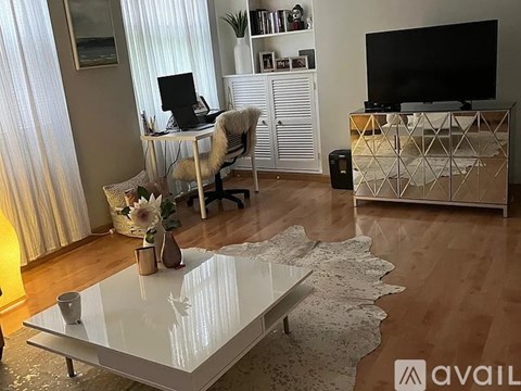 A modern living room with a glass coffee table and a TV on a cabinet.