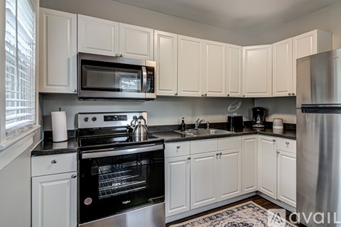 A kitchen with white cabinets and black appliances.