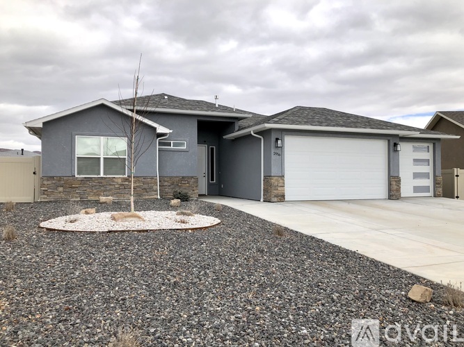 A grey house with a gravel driveway in front.