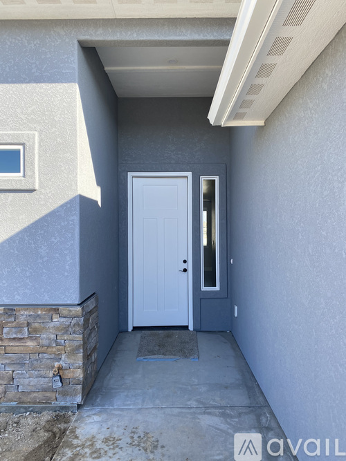 A white door is on the left side of a concrete walkway.