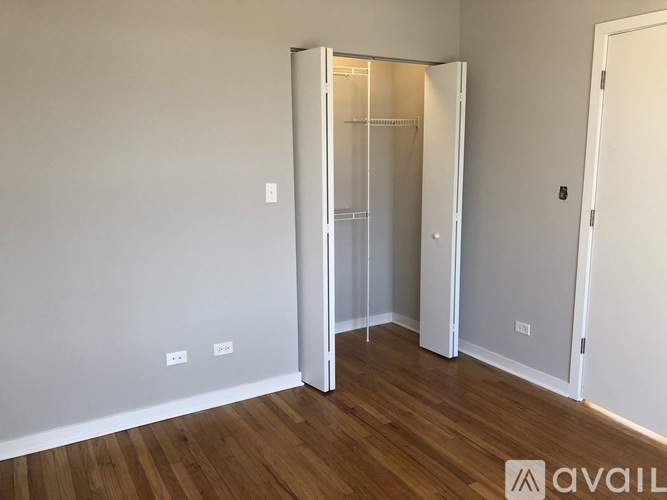 A room with a wooden floor and a white wall with a door and a wardrobe.