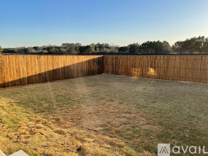 A backyard with a wooden fence and a grassy area.