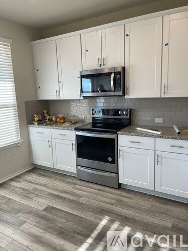 A kitchen with white cabinets and a black stove top oven.