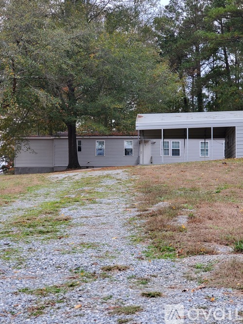 A two-story house with a garage is surrounded by trees and grass.