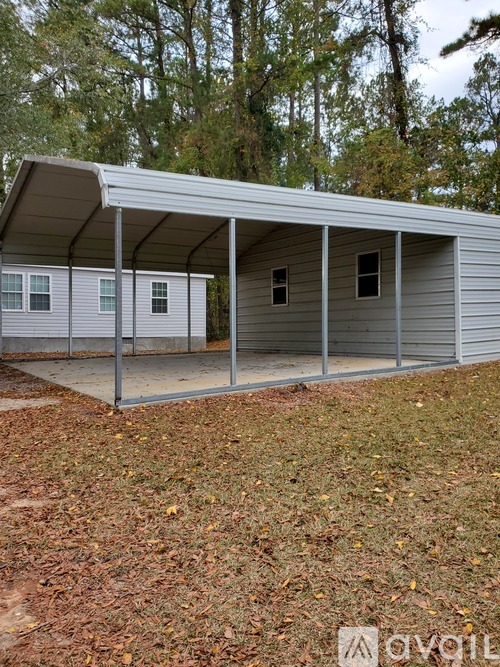A metal carport with a grey roof and a white wall.