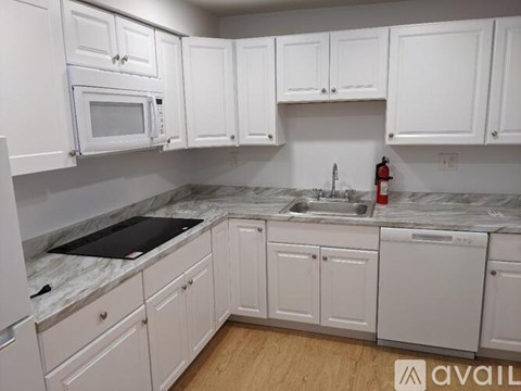 A kitchen with white cabinets and a marble countertop.