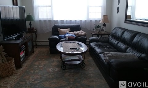 A living room with a black leather couch and a coffee table.