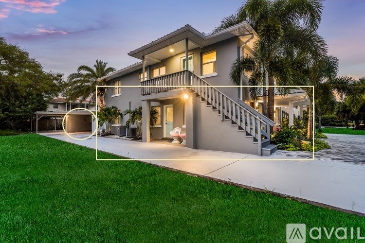 A modern house with a well-maintained lawn and palm trees in the background.