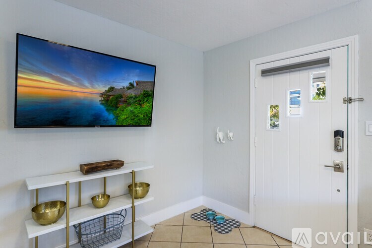 A room with a television on the wall and a door on the right.