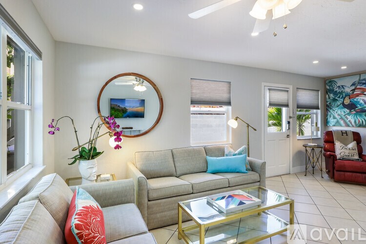 A living room with a grey couch, a coffee table, and a round mirror on the wall.