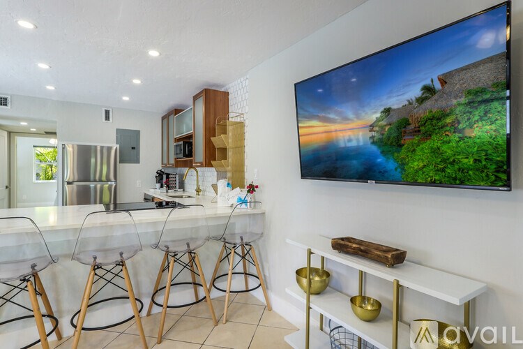 A modern kitchen with a bar area and a large TV mounted on the wall.