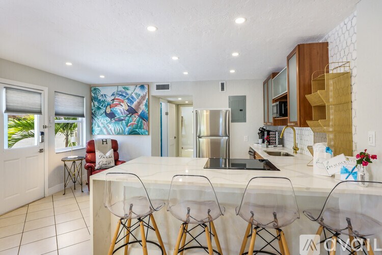 A kitchen with a white countertop and bar stools.