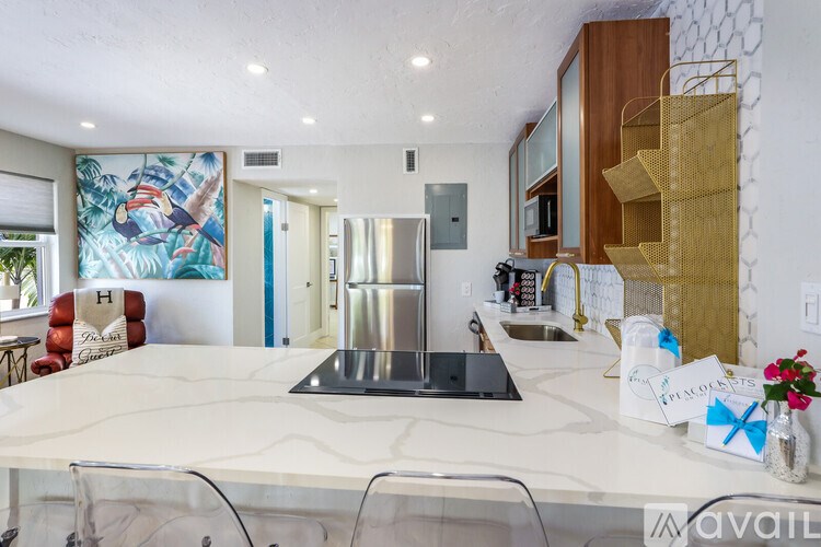 A kitchen with a marble countertop and a refrigerator in the middle.
