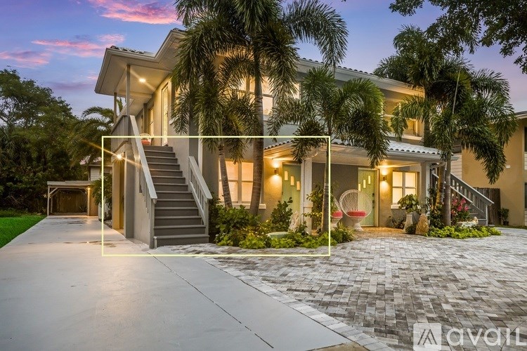 A modern house with a driveway and palm trees.