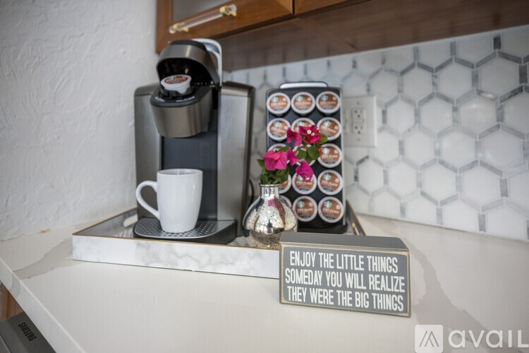 A coffee maker and cup on a counter with a sign that says "Enjoy the little things someday you will realize they were the big things".