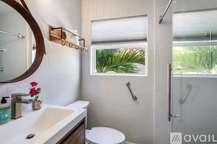 A bathroom with a white sink and a round mirror.